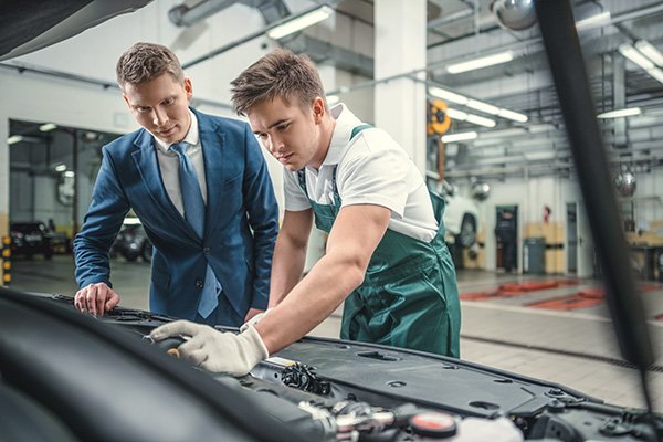 Mechanic and customer looking at car bonnet